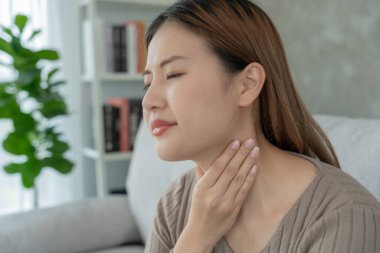Aisa denen kadın boğazı ağrıdığı için elini boynuna koydu. Dişi bademcik iltihabı iltihaba neden olur. Su alarak, antibiyotik alarak, doktora, virüse, korona virüsüne, gribe, gribe danışarak tedavi olunur.