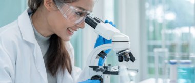 Bilimadamı ileri bilimsel laboratuvarda biyokimyasal örnekleri analiz ediyor. Tıbbi profesyonel kullanım mikroskobu virüsün mikrobiyolojik gelişimini gösteriyor. Fen laboratuvarında biyoteknoloji araştırması.