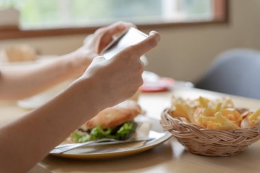 Restoran sahibi masadaki yemeklerin fotoğrafını çekiyor ve web sitesine yüklemek için akıllı telefon kullanıyor. Çevrimiçi gıda dağıtımı, sipariş servisi, nüfuz, gözden geçirme, sosyal medya, paylaşım, pazarlama, faiz.