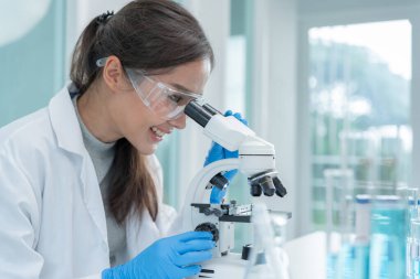 Bilimadamı ileri bilimsel laboratuvarda biyokimyasal örnekleri analiz ediyor. Tıbbi profesyonel kullanım mikroskobu virüsün mikrobiyolojik gelişimini gösteriyor. Fen laboratuvarında biyoteknoloji araştırması.