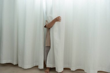 Küçük Asyalı çocuk, duvar evinde saklambaç oynuyor, sevimli çocuk evde eğleniyor. Mutlu aile çocuklarla, aktivitelerle, öğrenmeyle eğlenir.