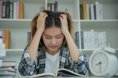 Asian student woman have anxiety because of exams, female prepare for test and learning lessons in the library. stress, despair, haste, misunderstanding reading, discouraged, expectation, knowledge