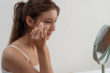 Kadın gülümsemesi iyi cilt için krem kullanır. Sağlıklı bir kadın yüzüne krem sürün ve makyaj yapın. Cilt kremi reklamı, kırışıklık önleyici, bebek yüzü, beyazlatma, nemlendirici, gözenekleri sıkılaştırma serumu.