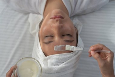 Güzel bir kadın spa ve yüz bakımı yaptırır. Sağlıklı bir kadının yüzüne krem sür. Cilt kremi reklamı, kırışıklık önleyici, bebek yüzü, beyazlatma, nemlendirici, gözenekleri sıkılaştırma serumu.