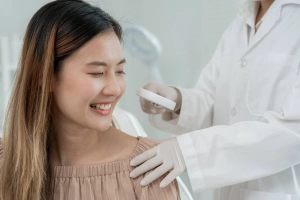 美しいアジアの女性はスキンケアを受ける間に笑顔 皮膚の専門家は 皮膚アレルギー ステロイドアレルギー 敏感な皮膚 化学アレルギー 皮膚炎から拡大ガラスに見えるかゆみのある皮膚を使用しています — ストック写真