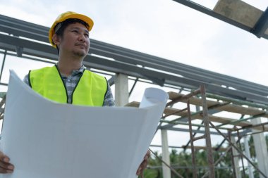 Müfettiş ya da mühendis mavi baskı kullanarak inşaat ve kalite güvencesini denetliyor. Mühendis, mimar ya da irtibat kurucu ev sahibine teslim etmeden önce evi inşa etmek için çalışıyor.