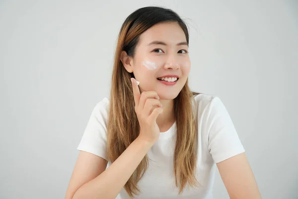 美しいアジアの女性の笑顔は良い肌のためにクリームを使用します 健康な女性の顔は クリームとメイクを塗ります スキンクリーム 反しわ 赤ちゃんの顔のための広告 白くする 保湿剤 きつく締め金で止める — ストック写真