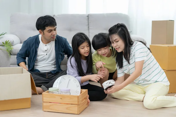Moving house, relocation. Family smile and play together after move to new home, inside the room was a cardboard box contain personal belongings and furniture. move in the new apartment, condominium