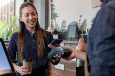 Kadın, kafeteryada nakit olmadan dijital ödeme yaparak kredi kartı ödemesini internet üzerinden yapıyor. İndirim biriktir. E cüzdan, teknoloji, online ödeme, kredi kartı, banka uygulaması. günlük yaşam ödemesi