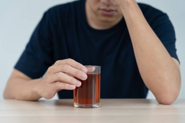 Depresyondaki genç Asyalı adam evde yalnız başına viski içmenin kötü hissettirdiğini, alkol içmenin sorunlu içki, alkolizm, hayat ve aile probleminden muzdarip olduğunu vurguladı.