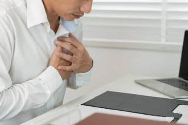 Kalp krizi belirtileriyle el ele tutuşan Asyalı adamın göğüs ağrısı var. Kalp rahatsızlığı, sızıntı, genişleme, genişlemiş kalp, göğsüne acı veren bir ekspresyoyla bastırma.