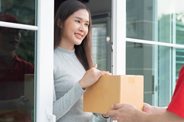 Happy smiling woman receives boxes parcel from courier in front house. Delivery man send deliver express. online shopping, paper containers, takeaway, postman, delivery service, packages
