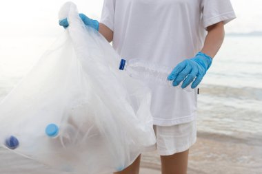 Su tasarrufu. Gönüllü olarak plajdaki çöpleri topluyor ve plastik şişeler suda yaşayan canlılara zarar gelmesini engelliyor. Dünya, Çevre, Yeşilci Gezegen, küresel ısınmayı azaltmak, Dünya 'yı kurtarmak