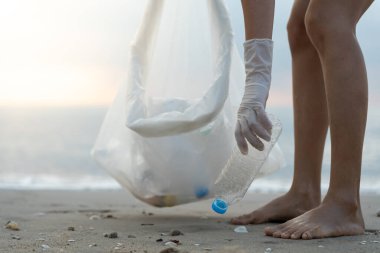 Su tasarrufu. Gönüllü olarak plajdaki çöpleri topluyor ve plastik şişeler suda yaşayan canlılara zarar gelmesini engelliyor. Dünya, Çevre, Yeşilci Gezegen, küresel ısınmayı azaltmak, Dünya 'yı kurtarmak