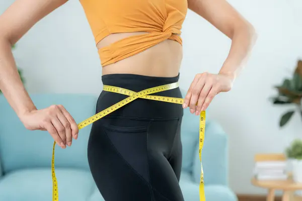 Diet and dieting. Beauty slim female body use tape measure. Woman in exercise clothes achieves weight loss goal for healthy life, crazy about thinness, thin waist, nutritionist.
