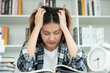 Asian student woman have anxiety because of exams, female prepare for test and learning lessons in the library. stress, despair, haste, misunderstanding reading, discouraged, expectation, knowledge