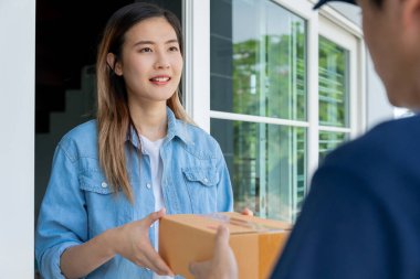 Happy smiling woman receives boxes parcel from courier in front house. Delivery man send deliver express. online shopping, paper containers, takeaway, postman, delivery service, packages