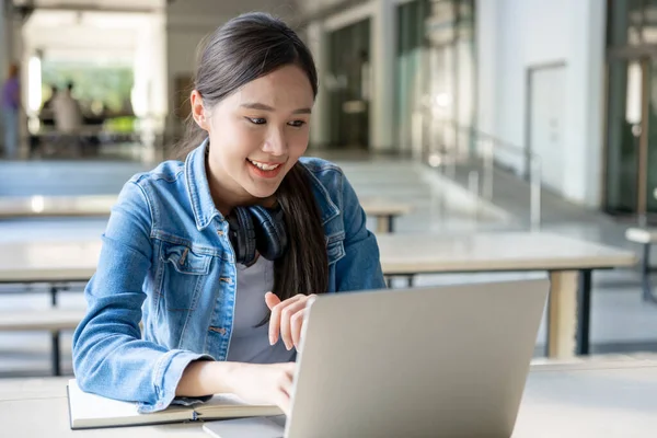 Beautiful Asian woman female student excited checking language test results on laptop. Smile girl happy study online. book in college campus. Portrait female on international Asia University. Education, study, school