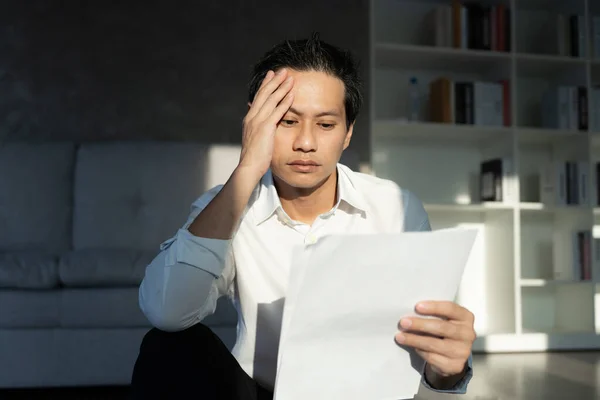 Stressed and headache asian man with large bills or invoices no money to pay to expenses and credit card debt. shortage, Financial problems, mortgage, loan, bankruptcy, bankrupt, poor, empty wallet