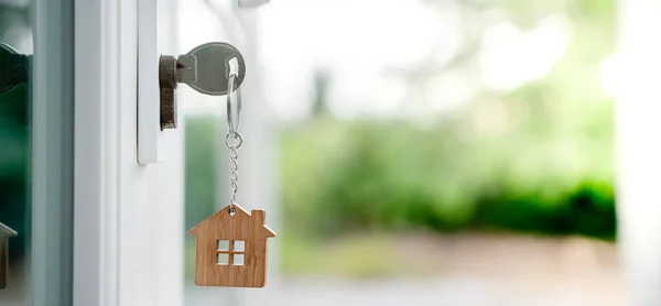 Landlord key for unlocking house is plugged into the door. Second hand house for rent and sale. keychain is blowing in the wind. mortgage for new home, buy, sell, renovate, investment, owner, estate