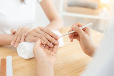 Kadın, güzellik merkezinde profesyonel güzellik manikürü ile bakım hizmeti alıyor. Güzellik salonunda jöle tedavisi için tırnak törpüsü kullanın. Manikürcü, çivi müşterisini güzelleştirir. vücut bakımı spa tedavisi