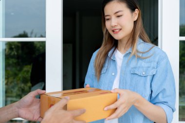 Happy smiling woman receives boxes parcel from courier in front house. Delivery man send deliver express. online shopping, paper containers, takeaway, postman, delivery service, packages