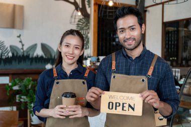 Asia couple owner show sign open on the first day of business. guarantees safety, cleanliness, open the coffee shop. open for New normal. Small business, welcome, restaurant, home made, family 