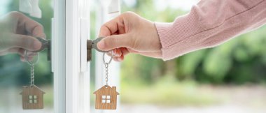 Evin kilidini açmak için ev sahibi anahtarı kapıya takılı. Kira ve satış için ikinci el ev. Sahibi yeni ev, satın al, sat, yenile, yatırım, sahip, mülk