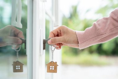 Evin kilidini açmak için ev sahibi anahtarı kapıya takılı. Kira ve satış için ikinci el ev. Sahibi yeni ev, satın al, sat, yenile, yatırım, sahip, mülk