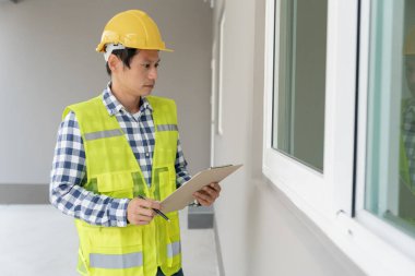 inspector or engineer is inspecting construction and quality assurance new house using a checklist. Engineers or architects or contactor work to build the house before handing it over to the homeowner