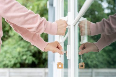 Evin kilidini açmak için ev sahibi anahtarı kapıya takılı. Kira ve satış için ikinci el ev. Sahibi yeni ev, satın al, sat, yenile, yatırım, sahip, mülk