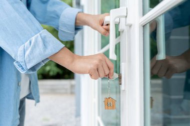 Evin kilidini açmak için ev sahibi anahtarı kapıya takılı. Kira ve satış için ikinci el ev. Sahibi yeni ev, satın al, sat, yenile, yatırım, sahip, mülk