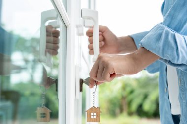 Evin kilidini açmak için ev sahibi anahtarı kapıya takılı. Kira ve satış için ikinci el ev. Sahibi yeni ev, satın al, sat, yenile, yatırım, sahip, mülk