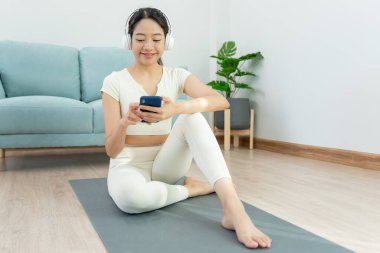 Sıska kadın telefonu kullanır ve yoga aktivitesinde dinlenme hisseder. Asyalı kadın sabah egzersiz yapıyor. denge, meditasyon, rahatlama, sakinlik, sağlık, mutluluk, rahatlama, sağlıklı yaşam tarzı, diyet, ince