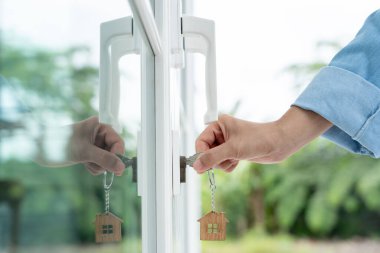 Evin kilidini açmak için ev sahibi anahtarı kapıya takılı. Kira ve satış için ikinci el ev. Sahibi yeni ev, satın al, sat, yenile, yatırım, sahip, mülk