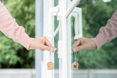 Evin kilidini açmak için ev sahibi anahtarı kapıya takılı. Kira ve satış için ikinci el ev. Sahibi yeni ev, satın al, sat, yenile, yatırım, sahip, mülk