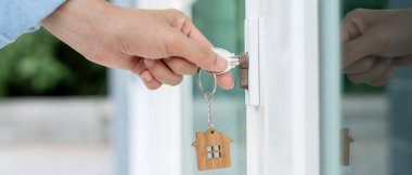 Evin kilidini açmak için ev sahibi anahtarı kapıya takılı. Kira ve satış için ikinci el ev. Sahibi yeni ev, satın al, sat, yenile, yatırım, sahip, mülk