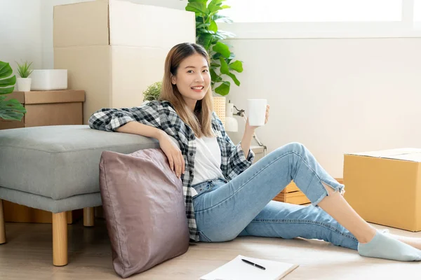 Moving house, relocation. Woman feel good and recreation on new apartment, inside the room was a cardboard box containing personal belongings and furniture. move in the house or condominium