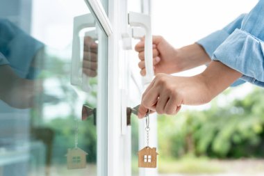 Evin kilidini açmak için ev sahibi anahtarı kapıya takılı. Kira ve satış için ikinci el ev. Sahibi yeni ev, satın al, sat, yenile, yatırım, sahip, mülk