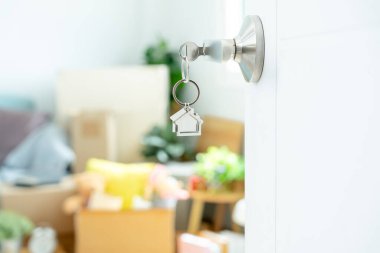 Moving house, relocation. The key was inserted into the door of the new house, inside the room was a cardboard box containing personal belongings and furniture. move in the apartment or condominium