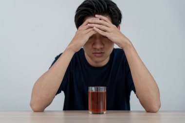 Depresyondaki genç Asyalı adam evde yalnız başına viski içmenin kötü hissettirdiğini vurguladı alkol içmek sorunlu içki, alkolizm, hayat ve aile sorunlarından muzdarip.