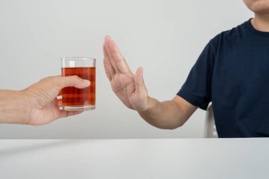 Adam hayır demeyi reddediyor ve alkollü viski içmekten kaçınıyor, el işareti yapan erkek, alkolizm tedavisi, alkol bağımlılığı, içkiyi bırakmak, alkol içmeyi bırakmak. İçkiyi reddet, sağlıksız, reddedilmiş