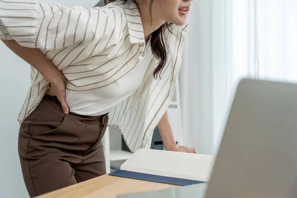 stock image woman holding her lower back while and suffer from unbearable pain health and problems, chronic back pain, backache in office syndrome, scoliosis, herniated disc, muscle inflammatio