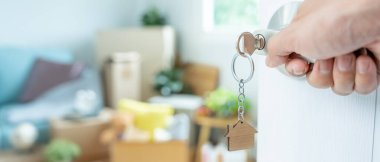 Taşınmak, taşınmak. Anahtar yeni evin kapısına yerleştirilmiş, odanın içinde kişisel eşyalar ve mobilyalar içeren bir karton kutu vardı. Daireye gir, afiş.