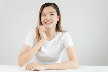 Güzel Asyalı kadın gülümsüyor, cilt kremi kullanıyor. Sağlıklı bir kadın yüzüne krem sürün ve makyaj yapın. Cilt kremi reklamı, kırışıklık önleyici, bebek yüzü, beyazlatma, nemlendirici, gözenekleri sıkılaştırma serumu.