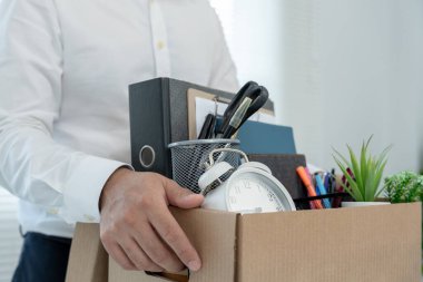 Stresli iş adamları şirketten istifa edecek. İçinde kişisel eşyalar olan kahverengi bir karton kutuyu kaldırıyor. İstifa, iş yerleştirme ve boşluklar kavramı.