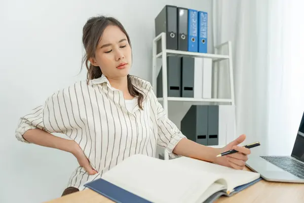 stock image Asia beautiful woman holding her lower back while and suffer from unbearable pain health and problems, chronic back pain, backache in office syndrome, scoliosis, herniated disc, muscle inflammation