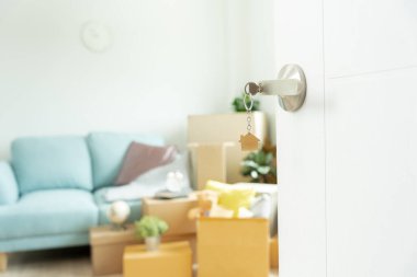 Moving house, relocation. The key was inserted into the door of the new house, inside the room was a cardboard box containing personal belongings and furniture. move in the apartment or condominium