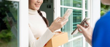 Mutlu bir gülümseme Asyalı kadın yemek parası için QR kodunu tarıyor. Teslimatçı ekspres teslimat gönderdi. Çevrimiçi dükkan, kağıt konteynır, paket servis, paket, elektronik para, dijital transfer