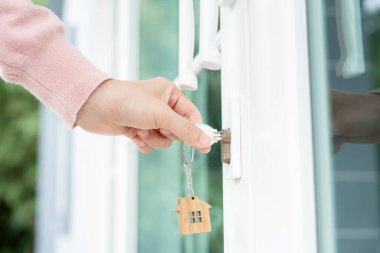 Evin kilidini açmak için ev sahibi anahtarı kapıya takılı. Kira ve satış için ikinci el ev. Sahibi yeni ev, satın al, sat, yenile, yatırım, sahip, mülk